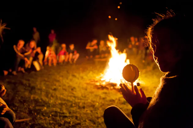 Mehrere Personen sitzen am Lagerfeuer