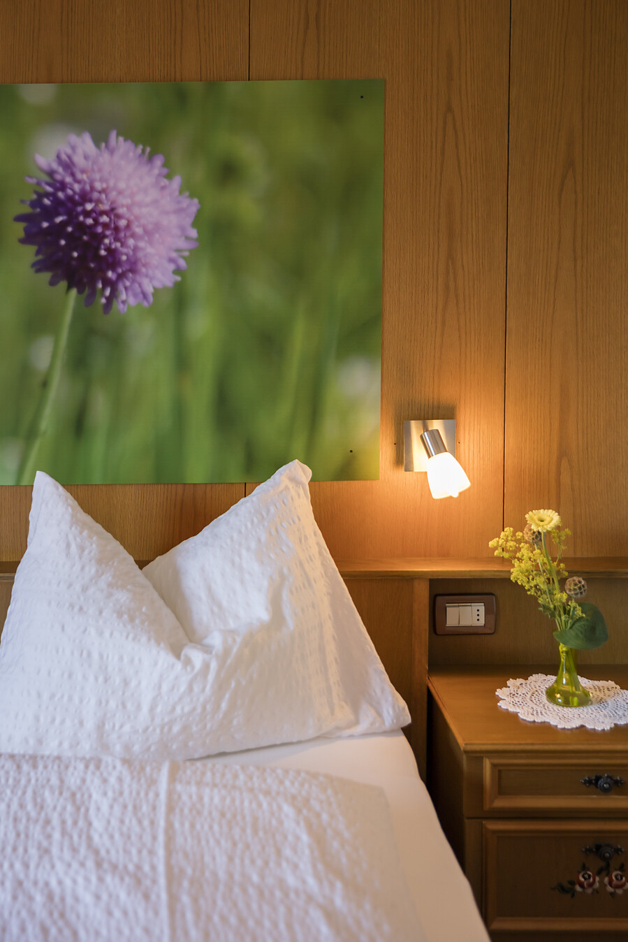 Bett mit Nachtkästchen und Blumen