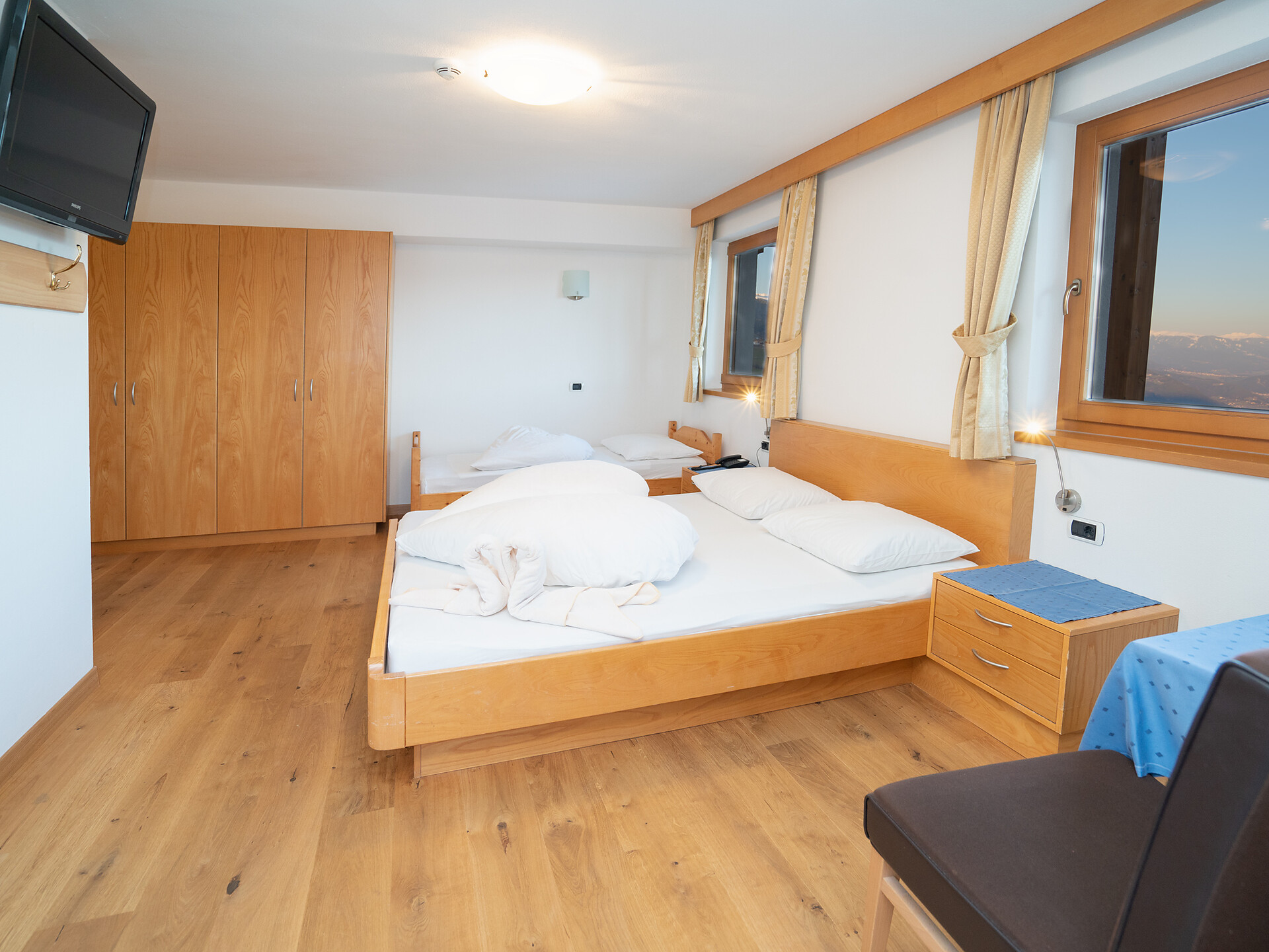 Dreibettzimmer mit Holzboden oder Teppich und Balkon