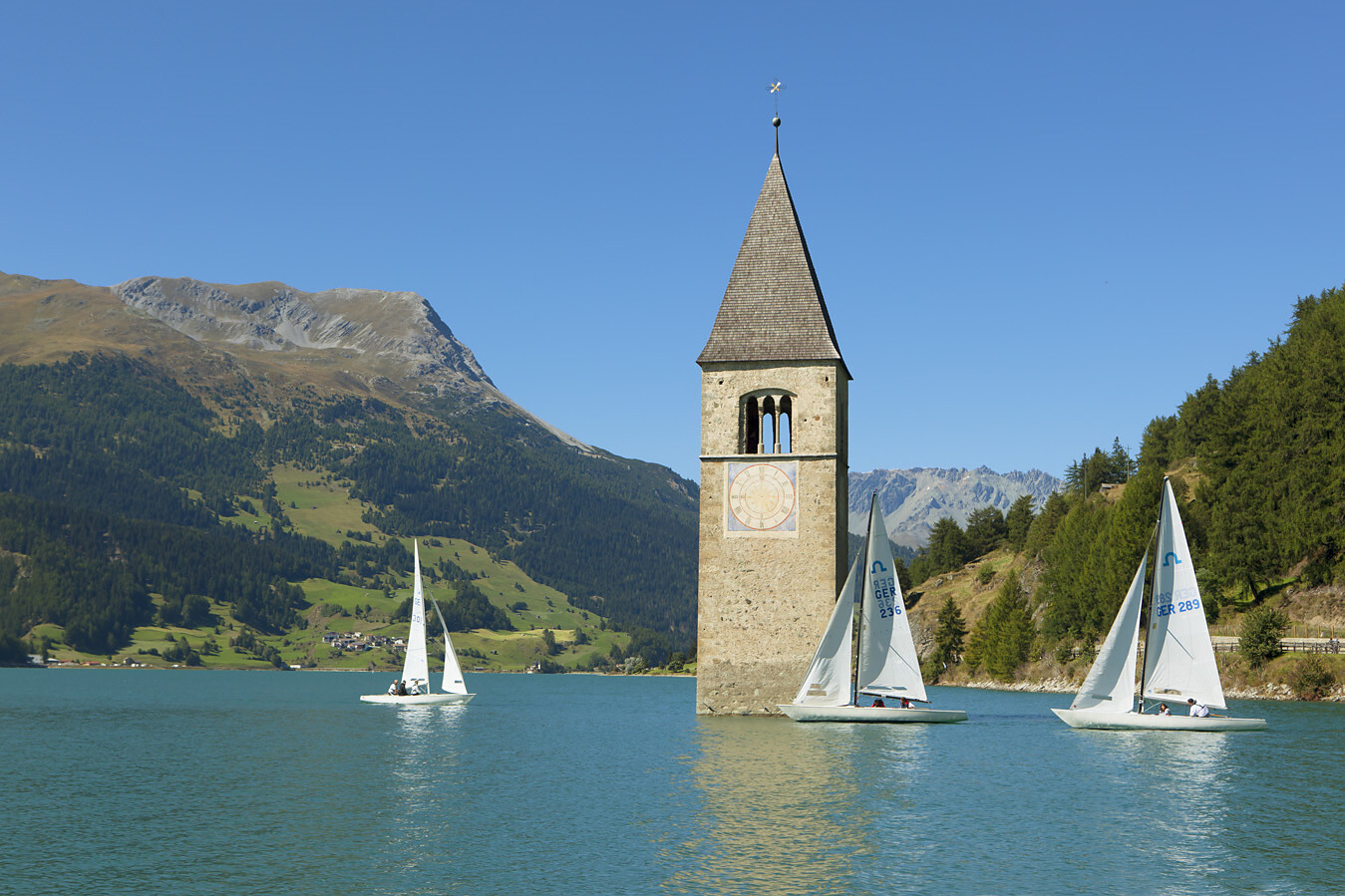 Barche a vela intorno al campanile nel lago di Resia