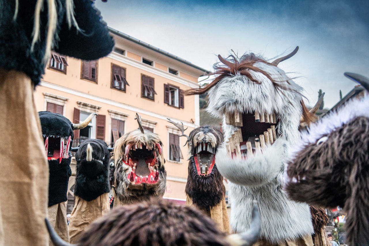 Mehrere sogenannte Schnappvieher-Figuren mit großen Holzzähnen sind am Faschingsdienstag beim Egetmannumzug in Tramin auf der Straße unterwegs.