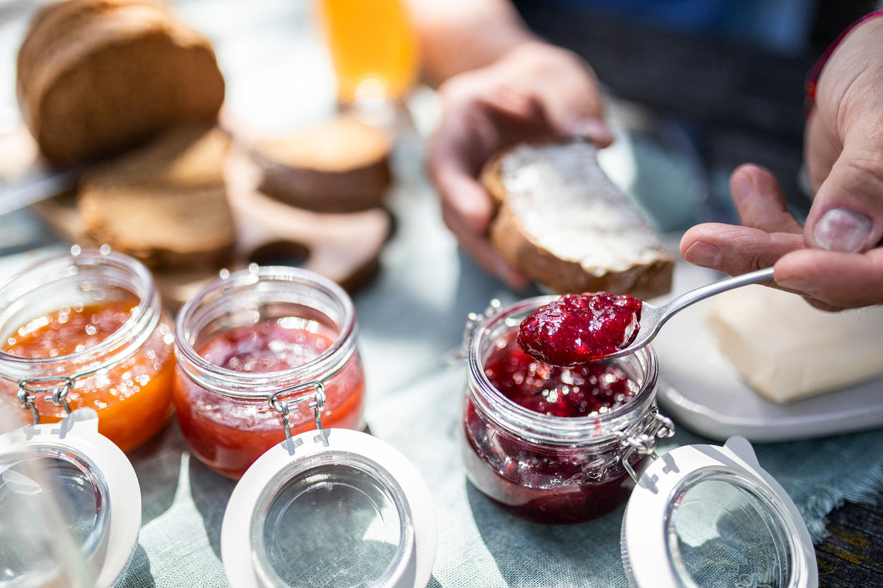 Eine Person nimmt einen Löffel Südtiroler Marmelade aus einem Glas für sein Frühstücksbrot