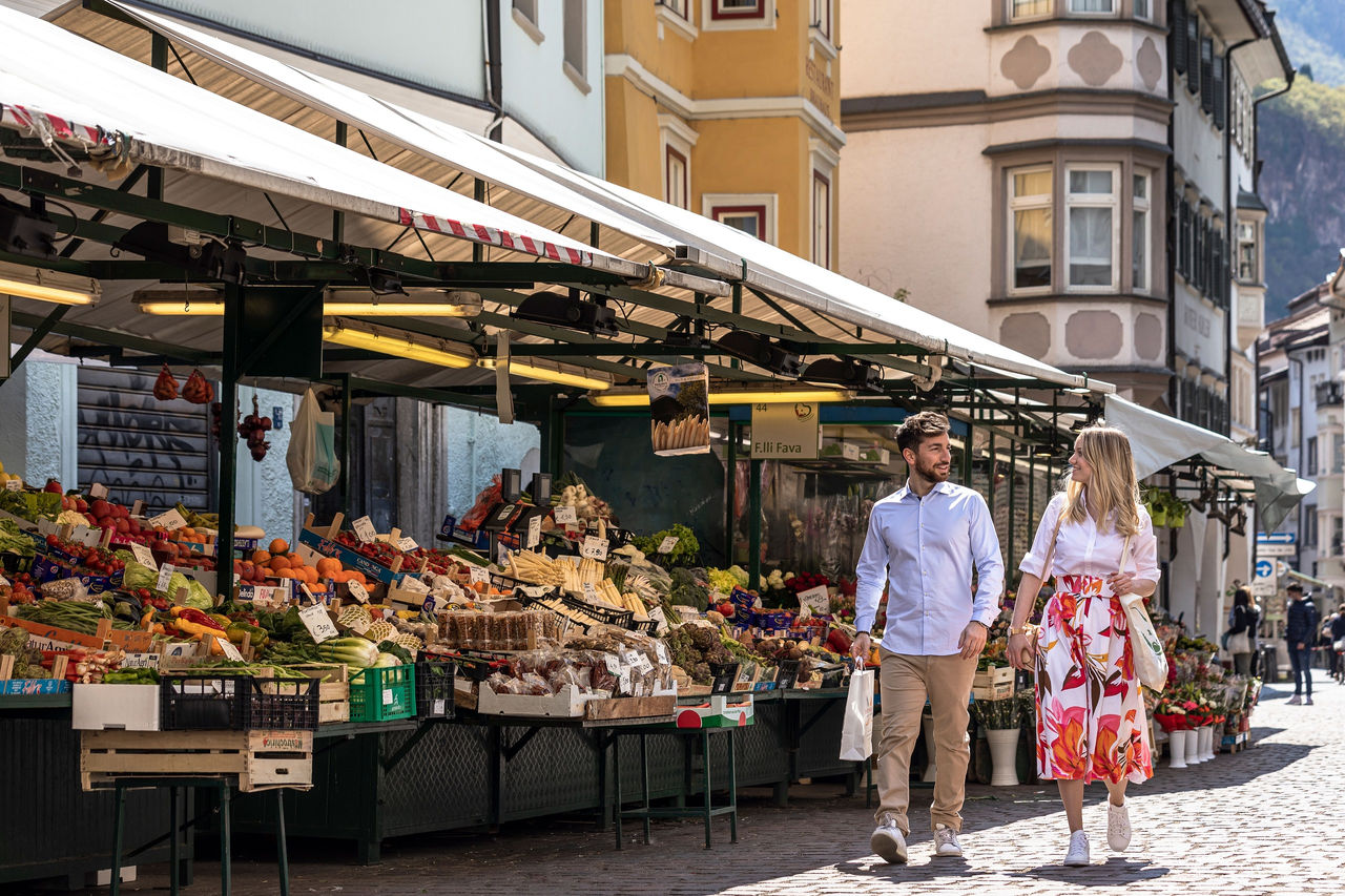Ein Mann und eine Frau bummeln über den Obstmarkt in Bozen im Sommer