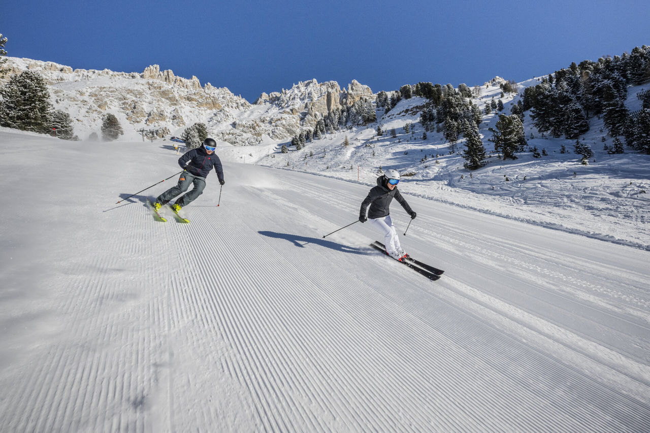 Zwei Skifahrer wedeln die frisch präparierte Abfahrt hinunter