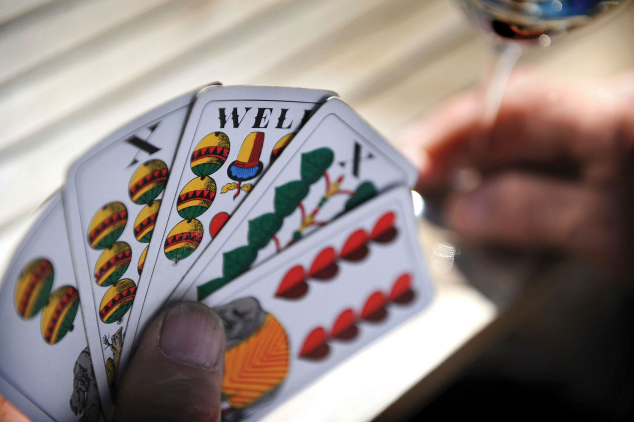 Beim traditionellen SÃ¼dtiroler Kartenspiel Watten hÃ¤lt ein Mann vier Karten in der Hand.