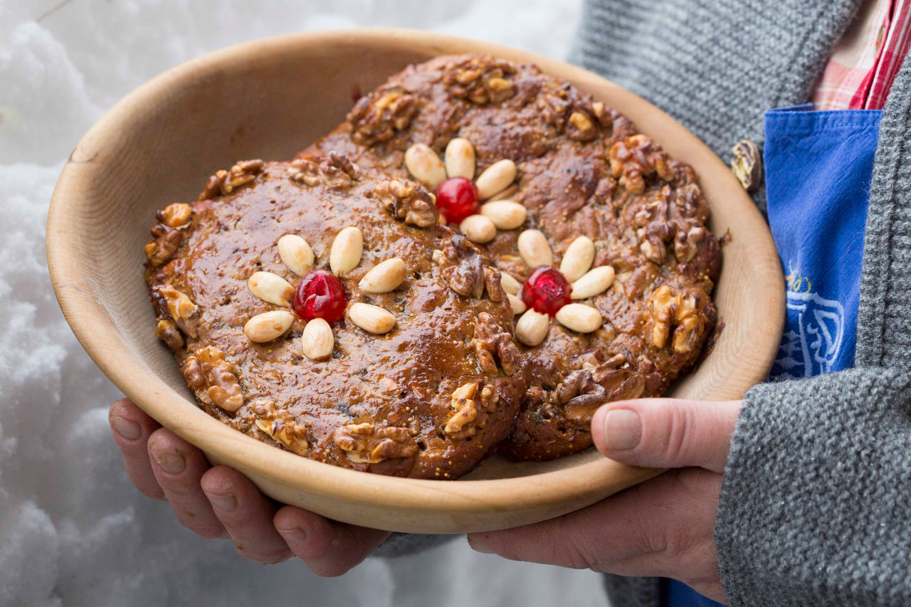 Ein Kind hält eine Schüssel mit Zelten, traditionellem Früchtebrot zu Weihnachten.