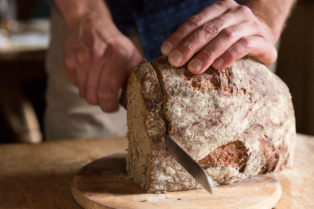 Eine Person schneidet ein Brot auf