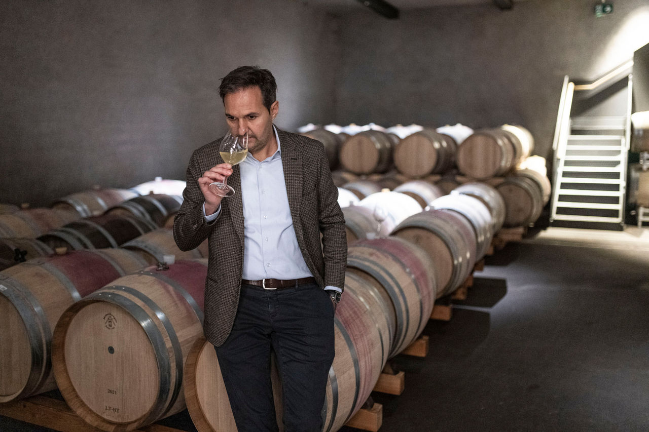 Rudi Kofler  Kellermeister der Kellerei Terlan testet den Wein mit mehreren Weinfässern im Hintergrund