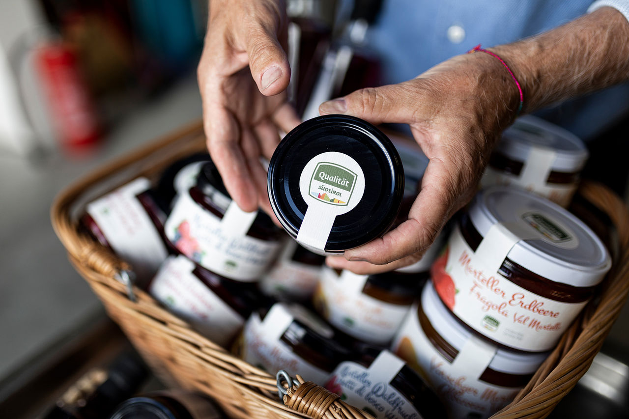 A person holds a jar of jam with the South Tyrol abel in his hand