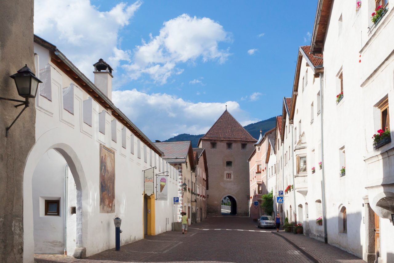 Mittelalterliche Stadtgasse von Glurns mit Torbogen der Stadtmauer am Ende der Straße