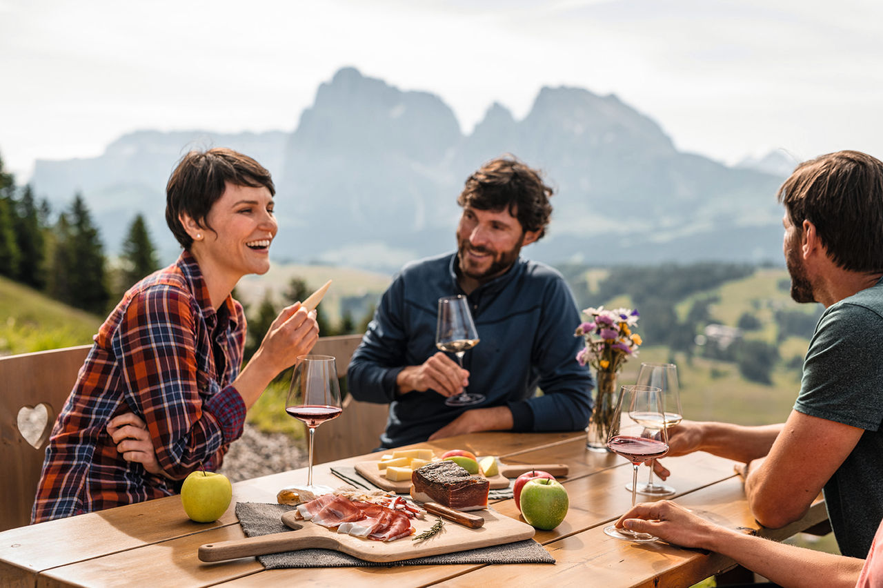 Vier Personen sitzen zusammen und genießen Südtiroler Produkte auf der Alm