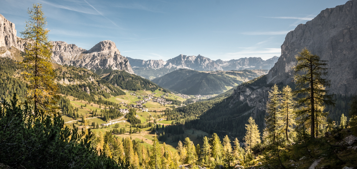 Dolomitenmassive im Sonnenlicht hinter einer begrünten Tallandschaft