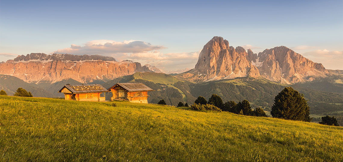 Zwei urige Almhütten in der Nachmittagssonne mit Aussicht auf die Dolomiten Unesco Weltnaturerben Sellastock und Langkofelgruppe
