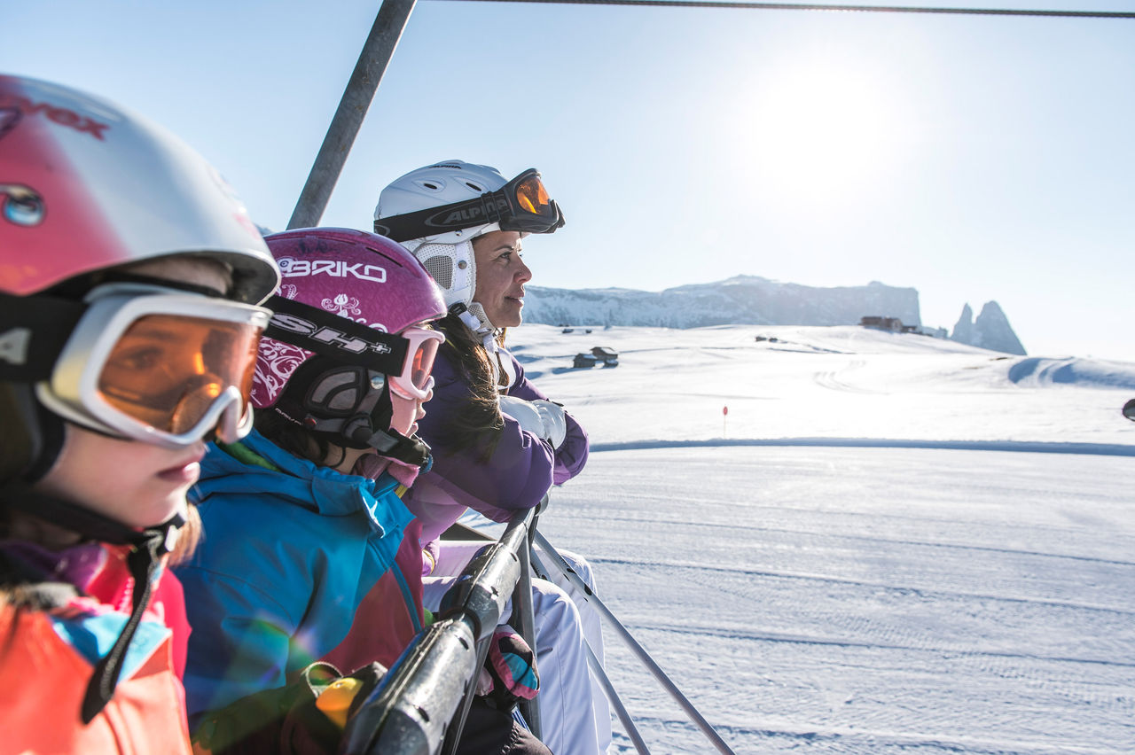 Mutter mit Kindern im Sessellift beim Skifahren auf der Seiser Alm