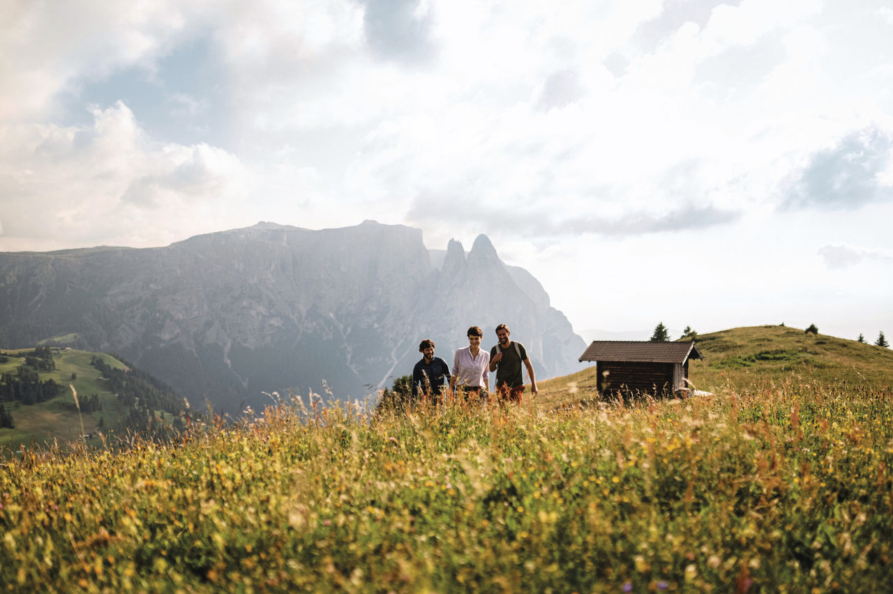 Drei Personen wandern auf der Seiser Alm