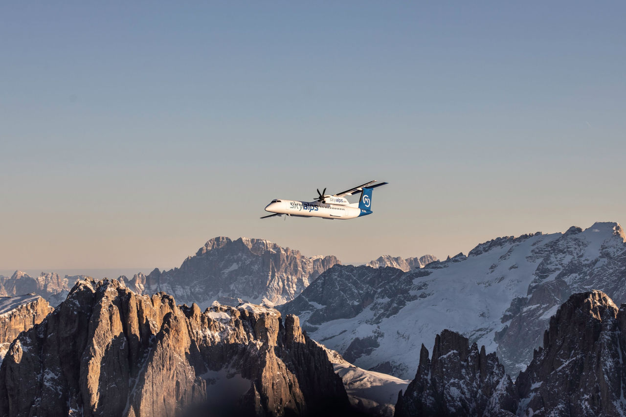 Ein Flugzeug der Skyalps-Fluggesellschaft im Flug über schneebedeckte Berge