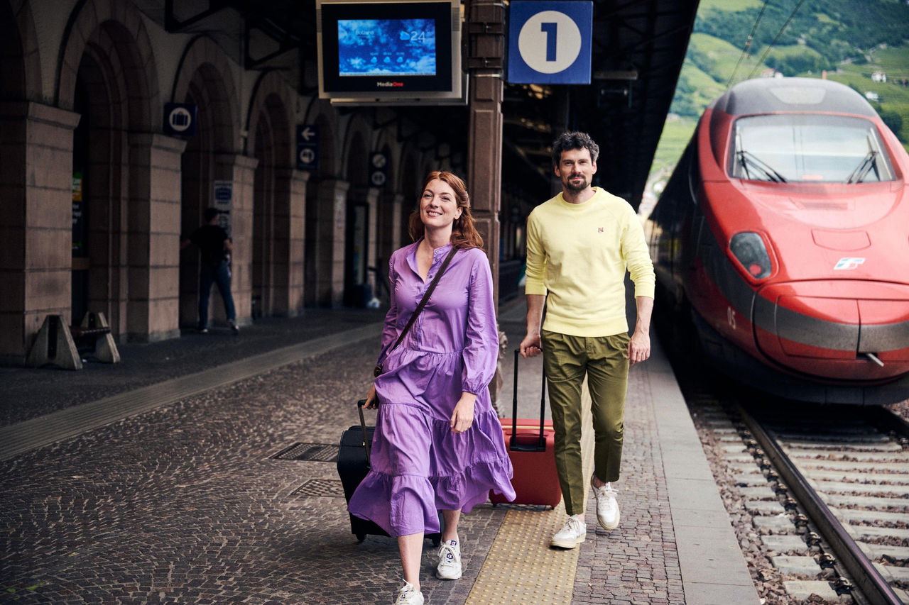 Eine Frau und ein Mann am Bahnsteig vom Zugbahnhof Bozen