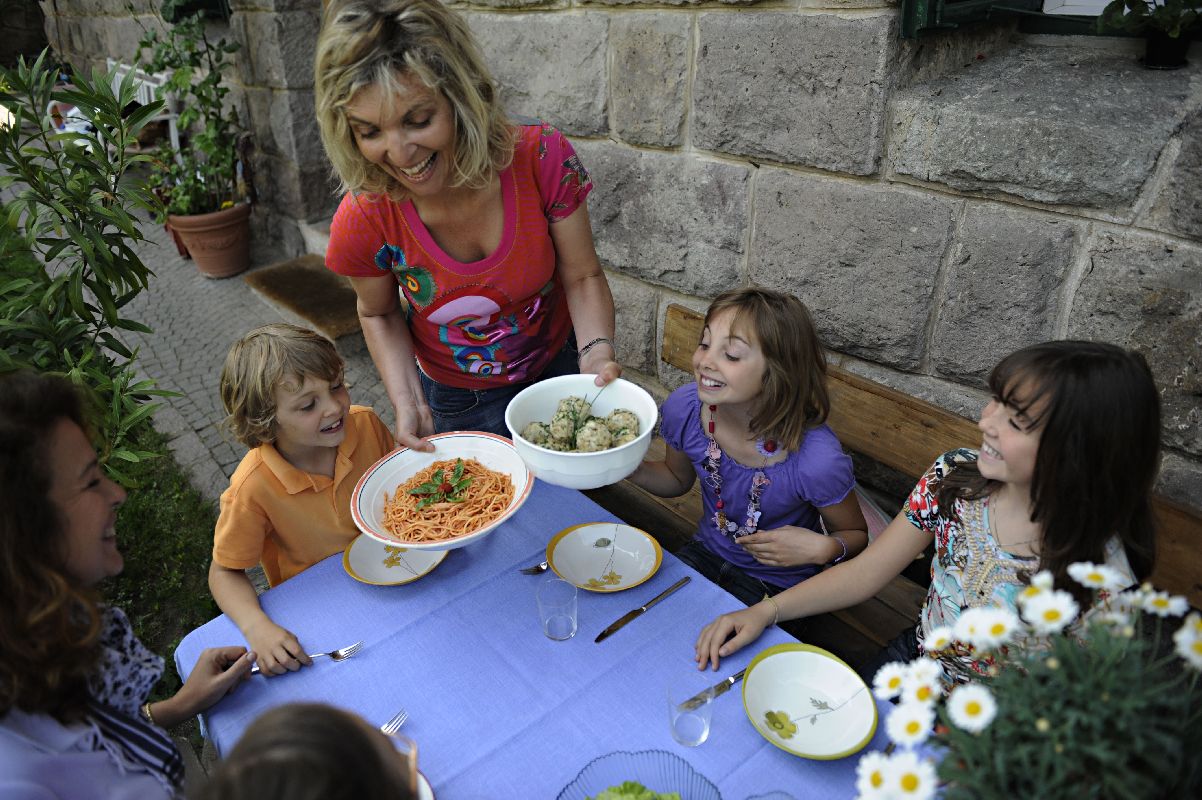 Eine Frau serviert klassische Südtiroler Knödel und klassisch italienische Spaghetti. 