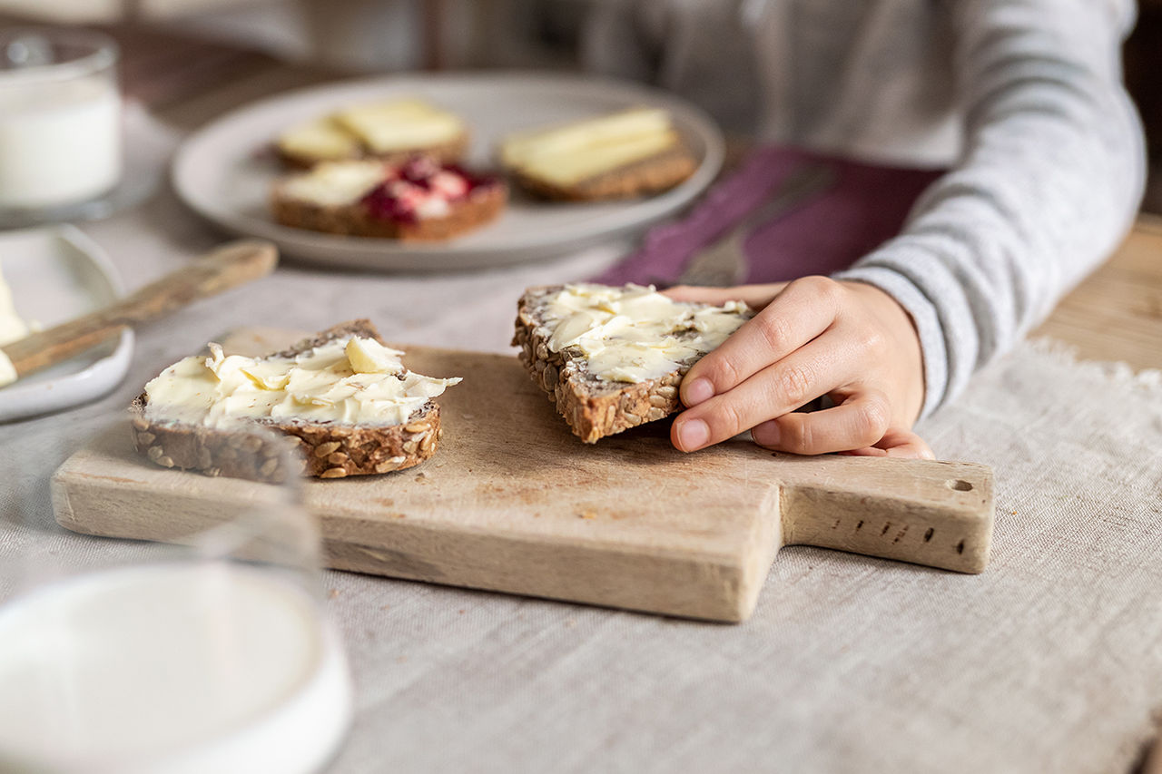 Eine Person nimmt sich ein Brot das mit Käse belegt ist