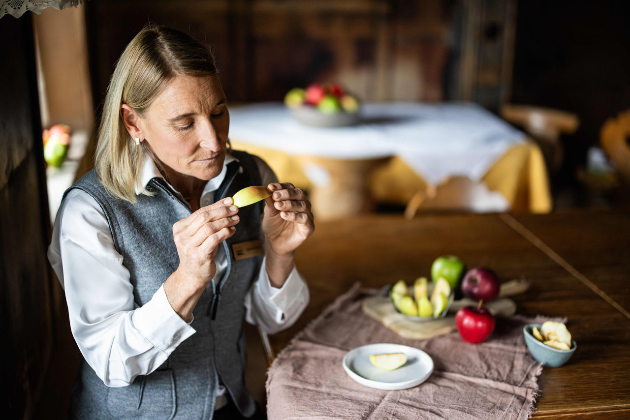 Eine Apfelsommelière verkostet ein Stück Apfel aus Südtirol in einer traditionellen Stube