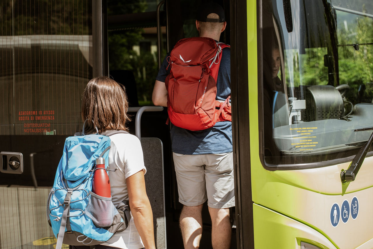 Zwei Fahrgäste steigen im Sommer in einen Nahverkehrsbus in Südtirol ein.