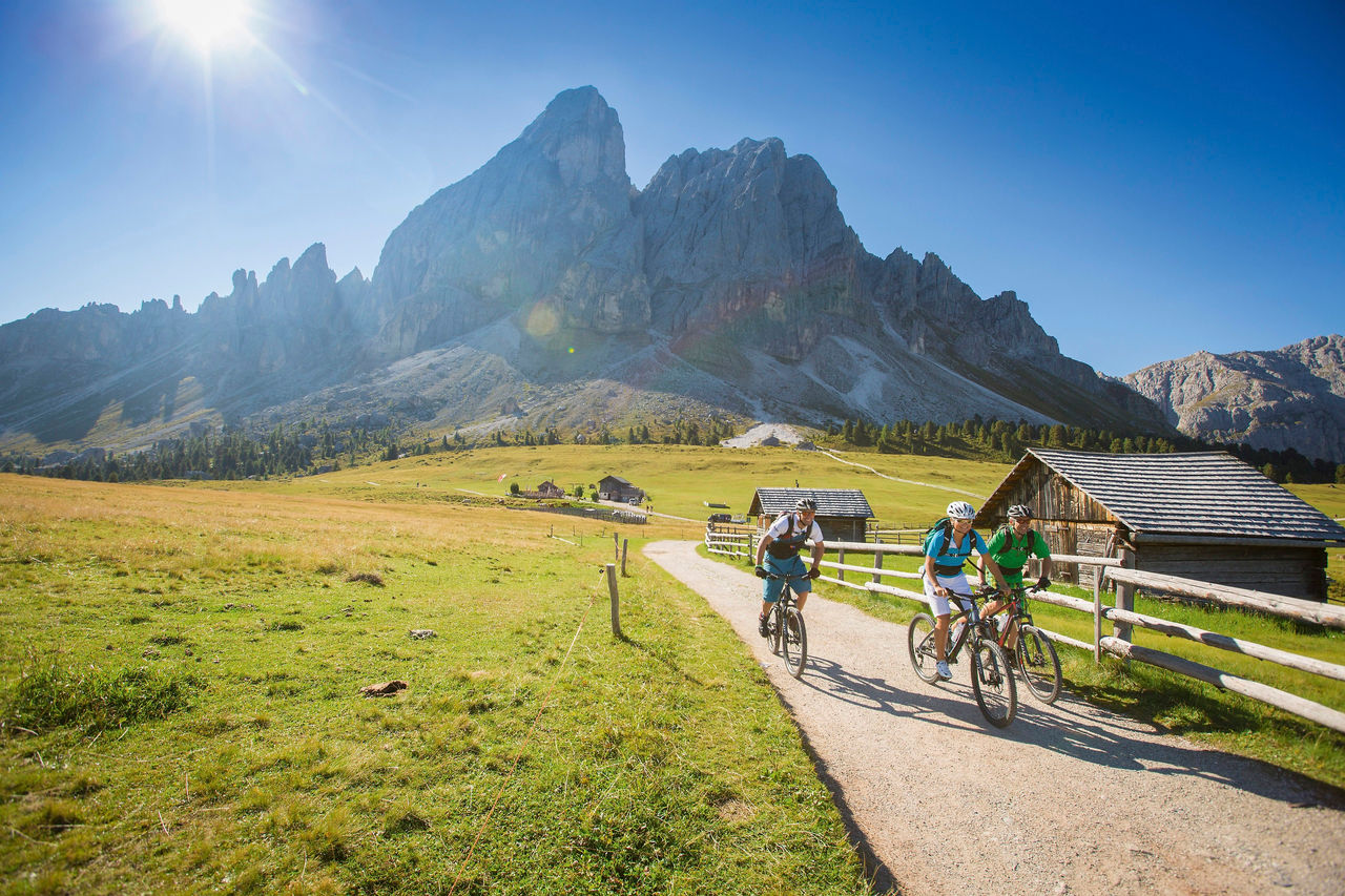 Drei Mountainbiker genießen eine Tour am Peitlerkofel, der im Hintergrund zu sehen ist.